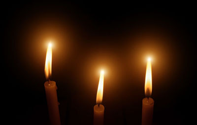 Close-up of lit candle against black background