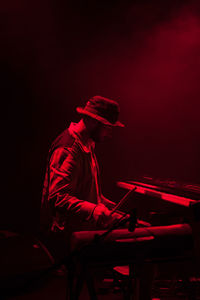 Side view of male musician holding stick while playing piano during concert