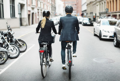 Rear view of business people riding bicycles on street