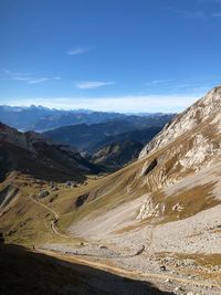 Scenic view of road by mountains against sky