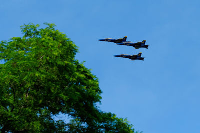 Low angle view of airplane flying against clear blue sky