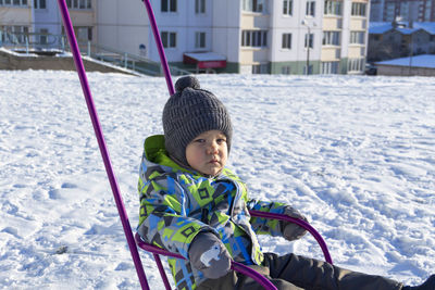 A small child sleds on white snow in winter and breathes fresh air.