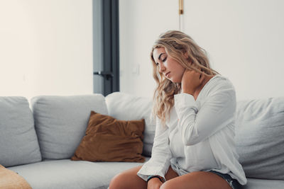 Young woman sitting on bed at home