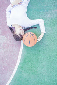 Directly above shot of young woman lying down at basketball court