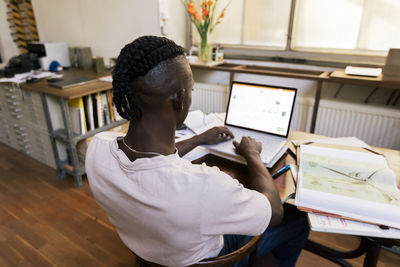 Rear view of man using laptop at office