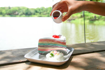 Midsection of person holding ice cream cone on table