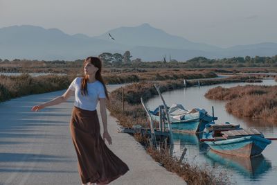 Young woman standing against lake