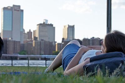 Rear view of woman lying on cityscape against sky