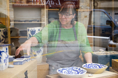 Artisan working in store seen through window