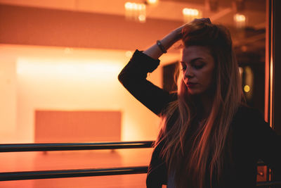 Portrait of young woman standing in illuminated room