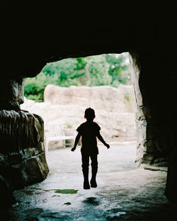 Rear view of silhouette man standing on rock