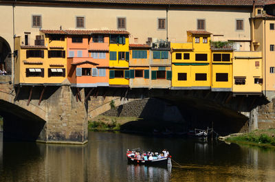 People on bridge over river against buildings in city