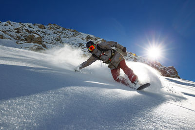 Man snowboarding on snow against sky