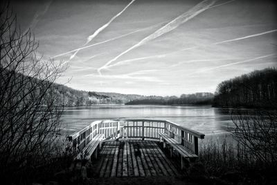 Footbridge over lake against sky