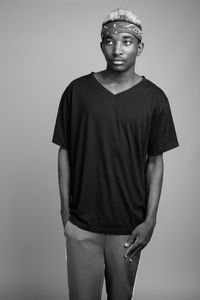 Young man standing against gray background