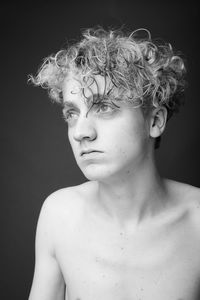 Portrait of shirtless young man against black background