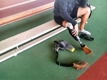 Low section of athlete with prosthetic leg sitting at running track