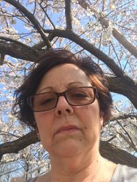 Low angle portrait of young woman wearing sunglasses against tree