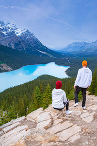 Rear view of people looking at mountains against sky