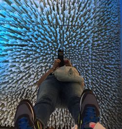 Low section of person photographing while standing on glass floor