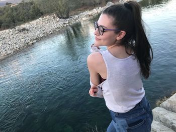 Rear view of young woman standing by lake