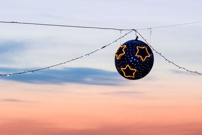 Low angle view of christmas decoration hanging against sky during sunset