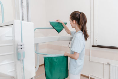 Side view of young woman using mobile phone while standing in bathroom