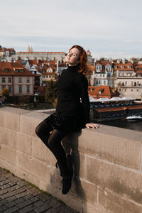 Full length portrait of young woman in city against sky