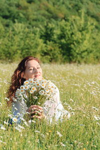 Portrait of young woman standing amidst plants on field