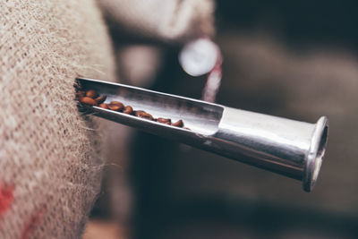 Close-up of pipe in sack of roasted coffee beans