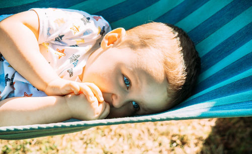 High angle portrait of baby boy lying on hammock in the sun