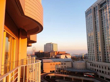 Modern buildings in city against sky during sunset