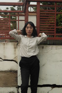 Portrait of young woman standing against built structure