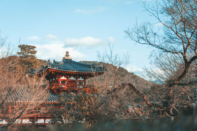 Built structure by trees and plants against sky