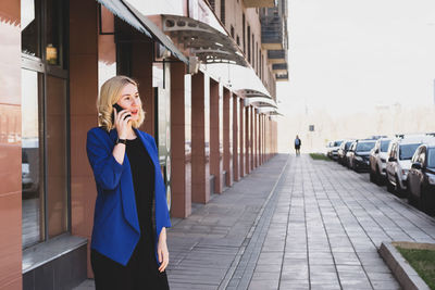 Full length of young woman using mobile phone