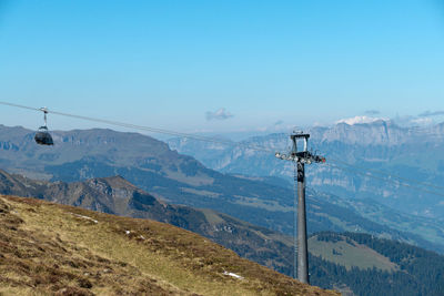 Overhead cable car in mountains against sky