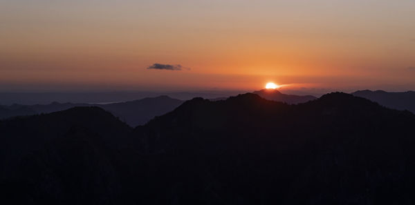 Scenic view of silhouette mountains against orange sky