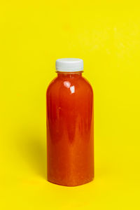 Close-up of glass bottle against yellow background