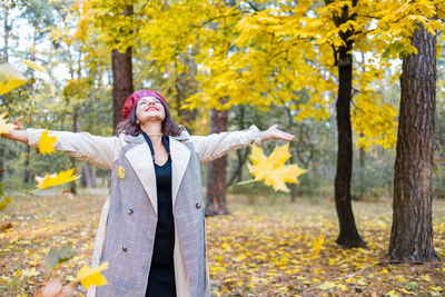 Portrait of young woman standing in forest during autumn