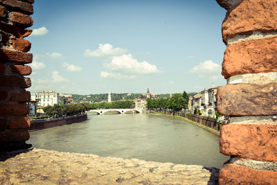 Arch bridge over river against buildings in city