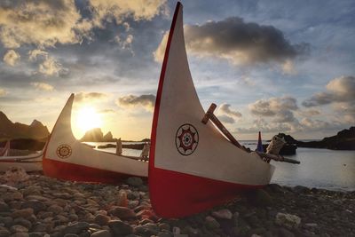 Ship moored on beach against sky during sunset