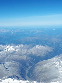 Aerial view of snowcapped mountains against blue sky