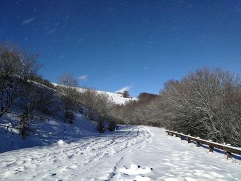 Snow covered landscape against clear blue sky