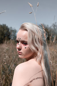 Portrait of beautiful woman on field against sky
