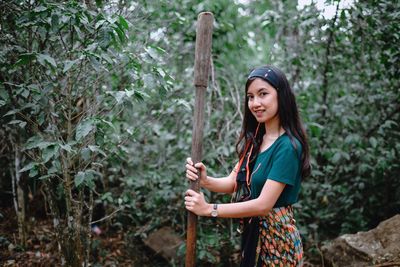 Young woman standing by tree in forest