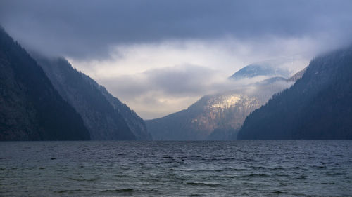 Scenic view of sea by mountains against sky