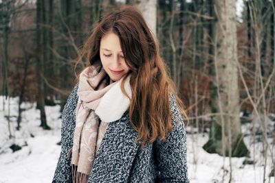 Beautiful young woman against trees during winter