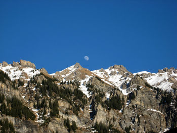 Low angle view of mountains against clear blue sky