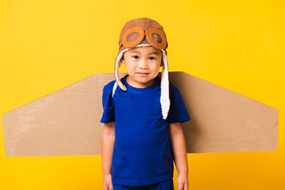 Portrait of boy wearing costume standing against yellow background