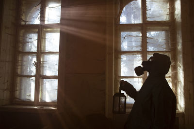 Side view of silhouette man holding window